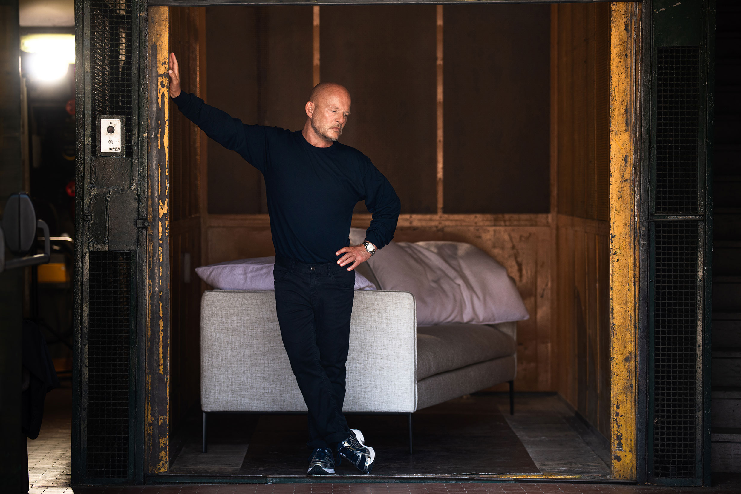 Vincent Van Duysen nell'ascensore merci con il divano Paul. Foto di Jeff Burton, tratta da Molteni Mondo, Rizzoli NY, 2024.